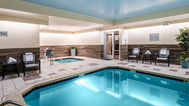 A pool area with a tiled floor, a small pool, lounge chairs, and a reception desk. - Fairfield Inn and Suites by Marriott Denver Aurora/ Medical Center (Aurora)