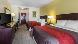 Une chambre d’hôtel avec deux lits, un bureau avec une télévision et une lampe.