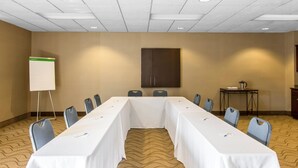Une salle de conférence équipée d’une longue table, de chaises, d’un tableau blanc et d’un meuble de rangement.