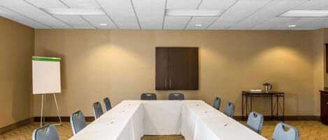 A conference room with a long table, chairs, a whiteboard, and a cabinet.