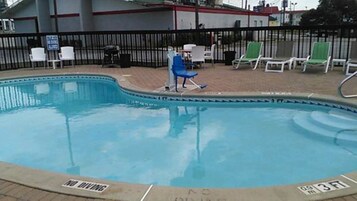 Una piscina al aire libre, sillones reclinables de piscina