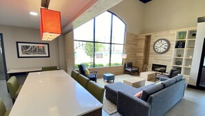 A modern living room with a large window, a dining area, and a fireplace.