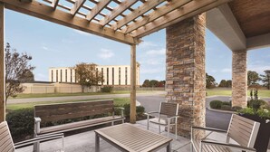 An outdoor patio with a wooden bench, a metal table, and two chairs.
