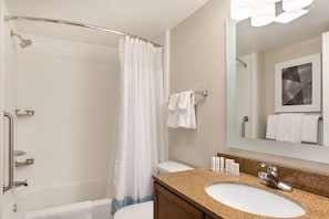 Un baño con ducha, inodoro, lavamanos y espejo.