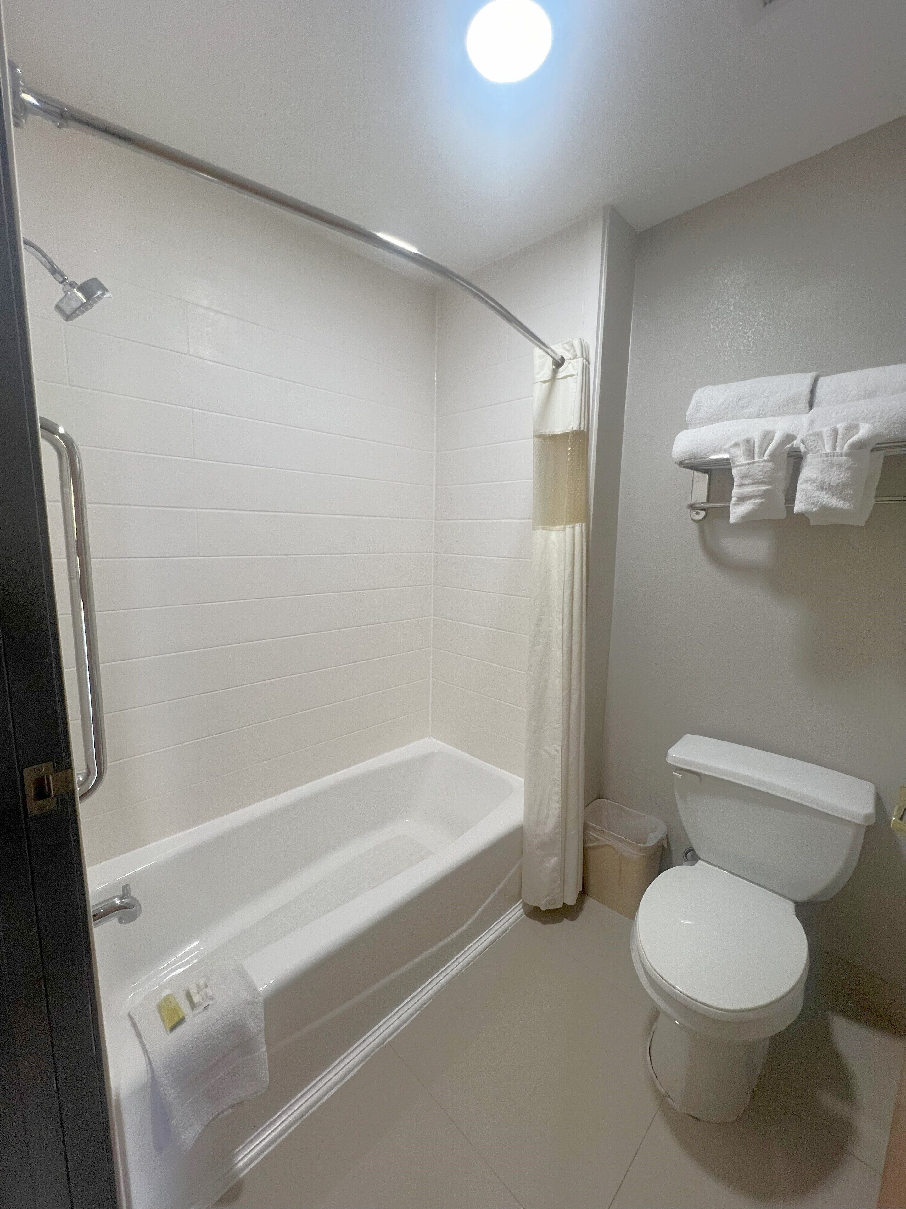 A bathroom with a bathtub, toilet, and towel rack.