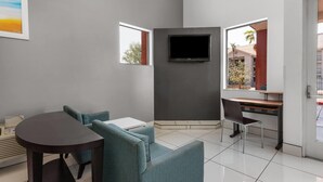 A modern living room with a flat-screen TV, a sofa, a dining table, and a desk.