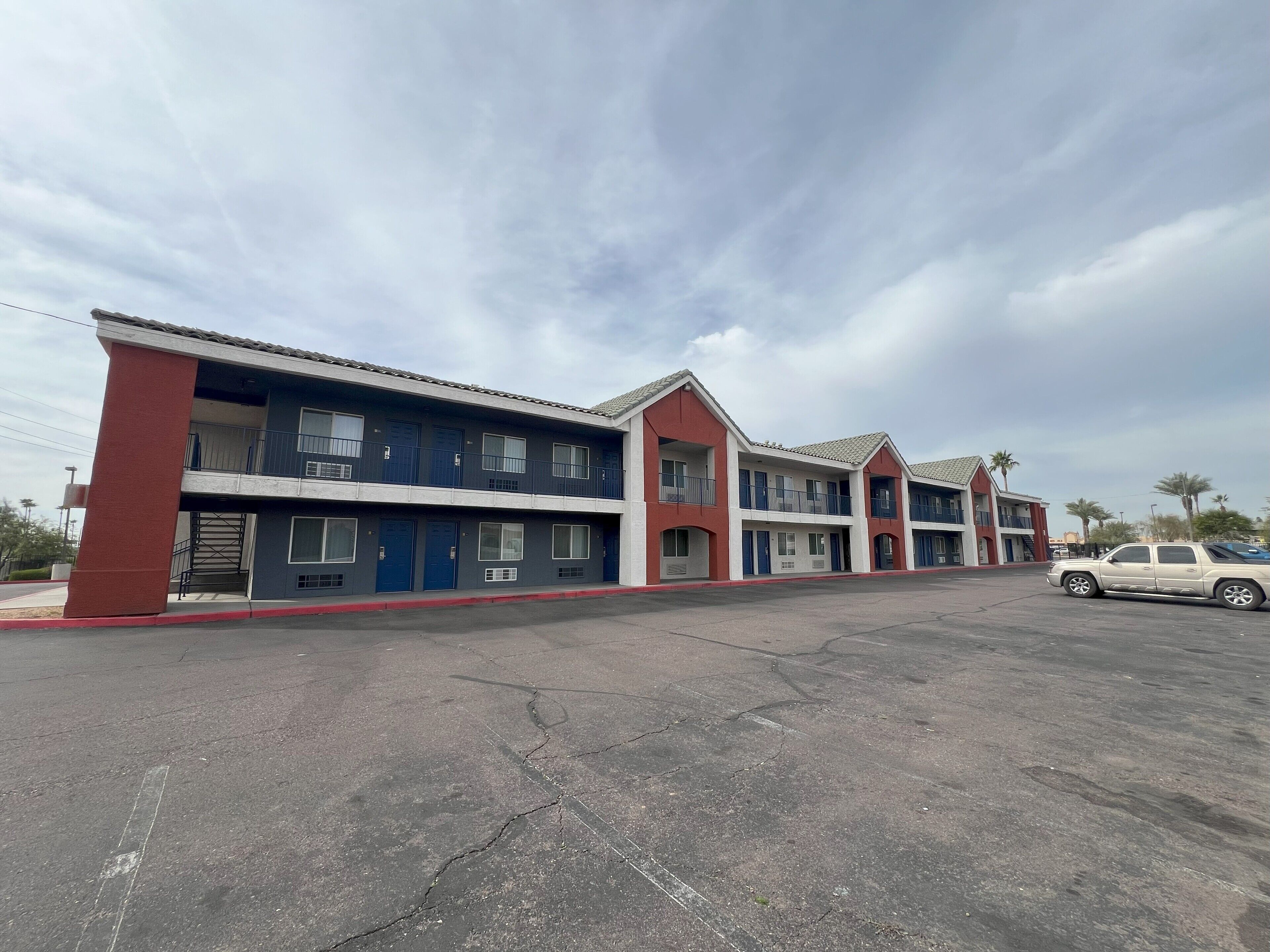 A multi-story motel with a red and blue facade, multiple balconies, and a parking lot.