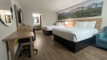 A hotel room with two beds, a desk, a chair, and a large painting on the wall.