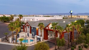 A hotel with a swimming pool, palm trees, and a view of the mountains.