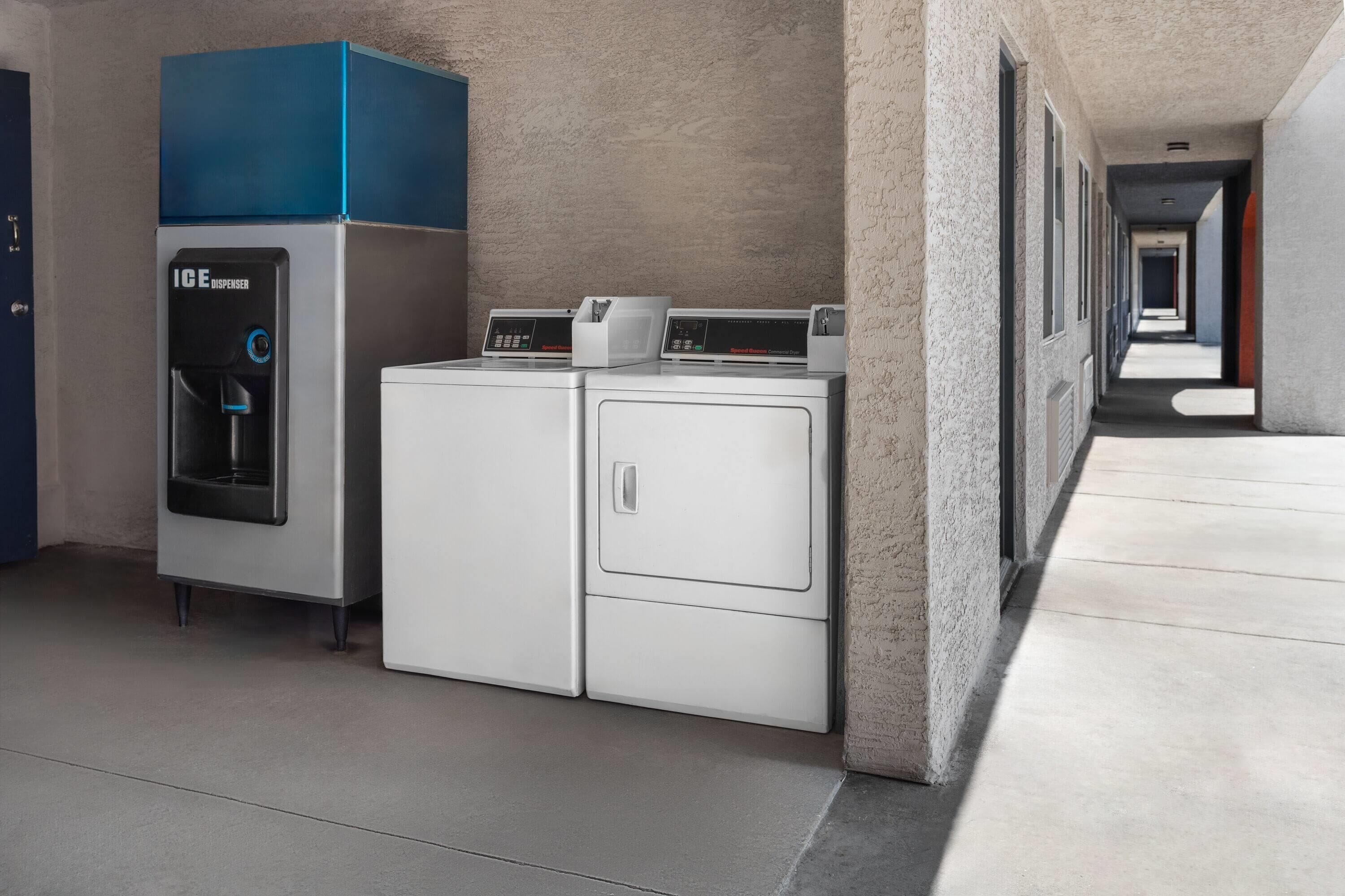 A laundry area with an ice dispenser and two washing machines.
