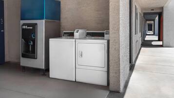A laundry area with an ice dispenser and two washing machines.