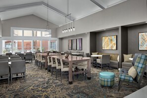 Um hall de hotel moderno com uma ampla área de refeições, assentos confortáveis e obras de arte nas paredes.