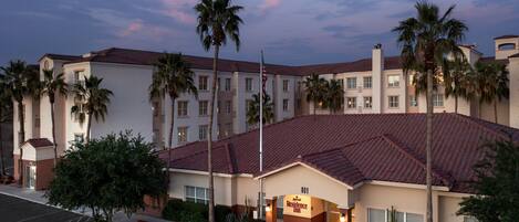 Een hotel met een rood pannendak, palmbomen en een bord waarop staat dat het een Marriott Residence Inn is.