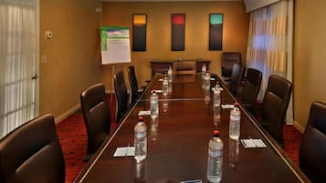 A conference room with a long table, chairs, water bottles, and a whiteboard.