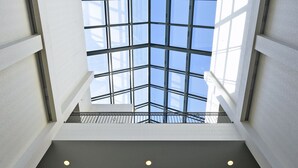 A modern atrium with a glass ceiling, allowing natural light to flood the space. - Maron Hotel And Suites (Danbury)