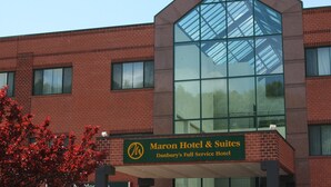 A Maron Hotel & Suites building with a prominent glass facade and a green signboard. - Maron Hotel And Suites (Danbury)