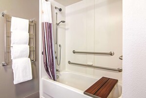 A bathroom with a white bathtub, a wooden shelf, and a towel rack with multiple towels.
