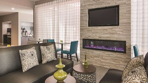 Un salon moderne avec un canapé, des fauteuils, une cheminée et un téléviseur à écran plat fixé au mur.