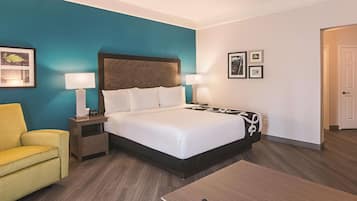 A hotel room with a bed, a nightstand, a chair, and a desk.