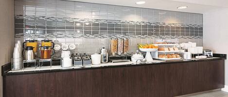 Uma cozinha moderna com bancada em madeira escura, eletrodomésticos de aço inoxidável e painel de vidro.