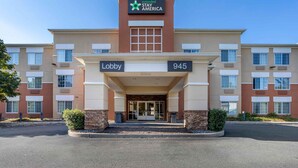 Un hôtel Stay America avec une entrée située dans le hall, portant le numéro 945, et un ciel bleu dégagé au-dessus.