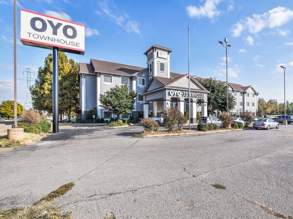 A townhouse with a sign reading "OYO TOWNHOUSE" and a parking lot in front.