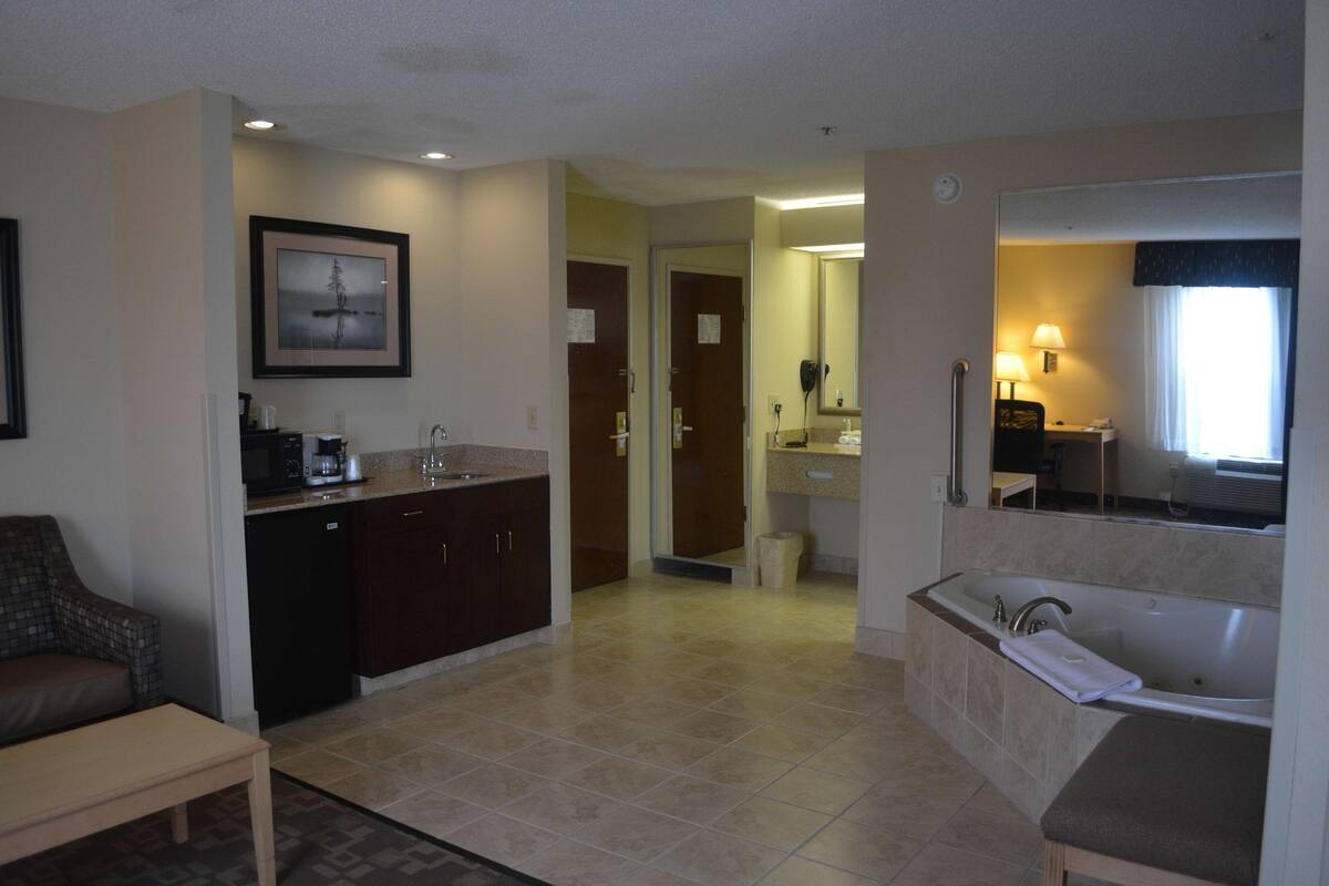 A hotel bathroom with a bathtub, sink, and mirror.