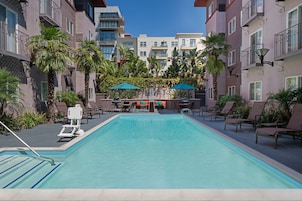 Una piscina al aire libre, sombrillas, sillones reclinables de piscina