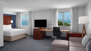 Una habitación de hotel con cama, escritorio, silla y sofá.