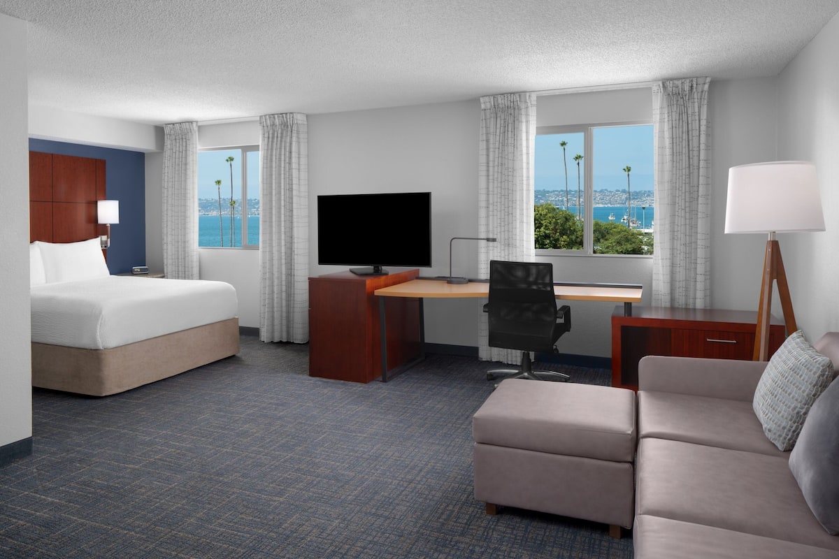 Een hotelkamer met een bed, bureau, stoel en bank.