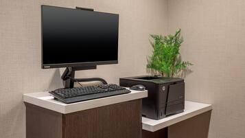 Un espacio de trabajo moderno con un monitor de pantalla plana, teclado y computador de escritorio HP sobre un escritorio blanco frente a una pared con textura.