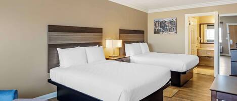 A hotel room with two beds, a desk, and a chair.