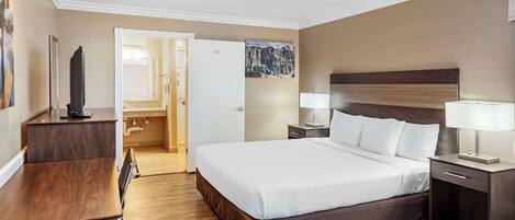A hotel room with a large bed, bedside tables with lamps, a desk, and a television.