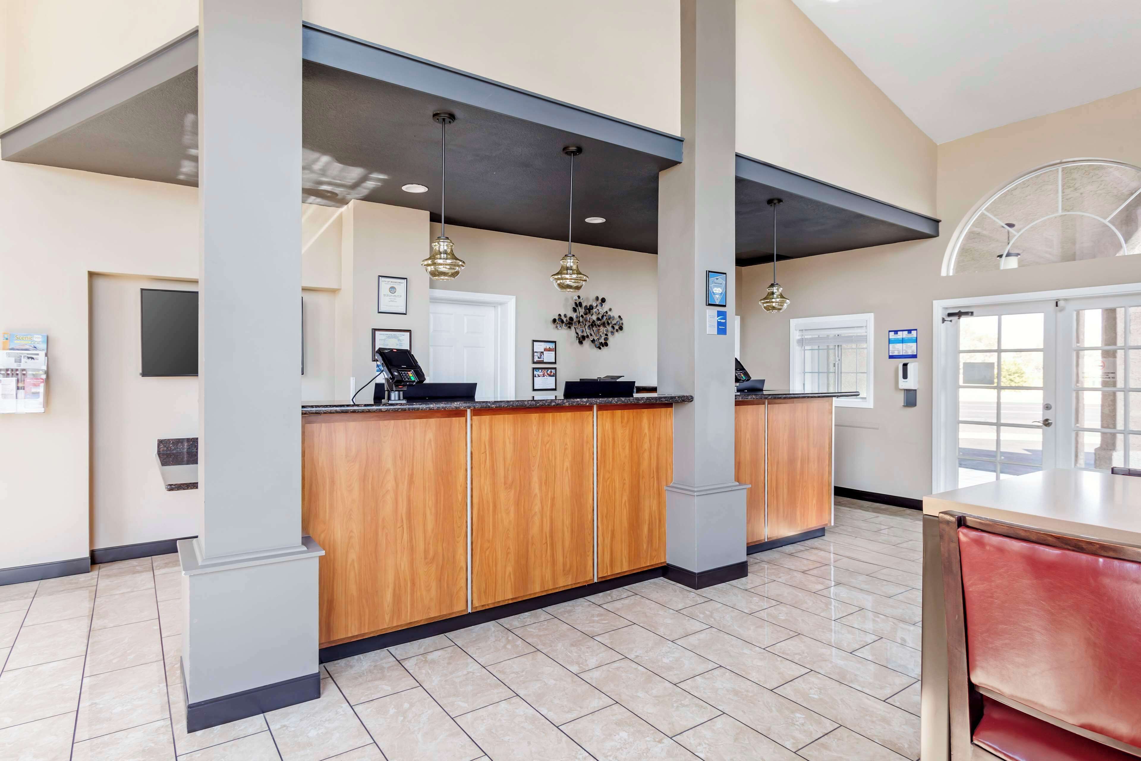A reception area with a wooden counter, a coffee machine, and a digital screen.