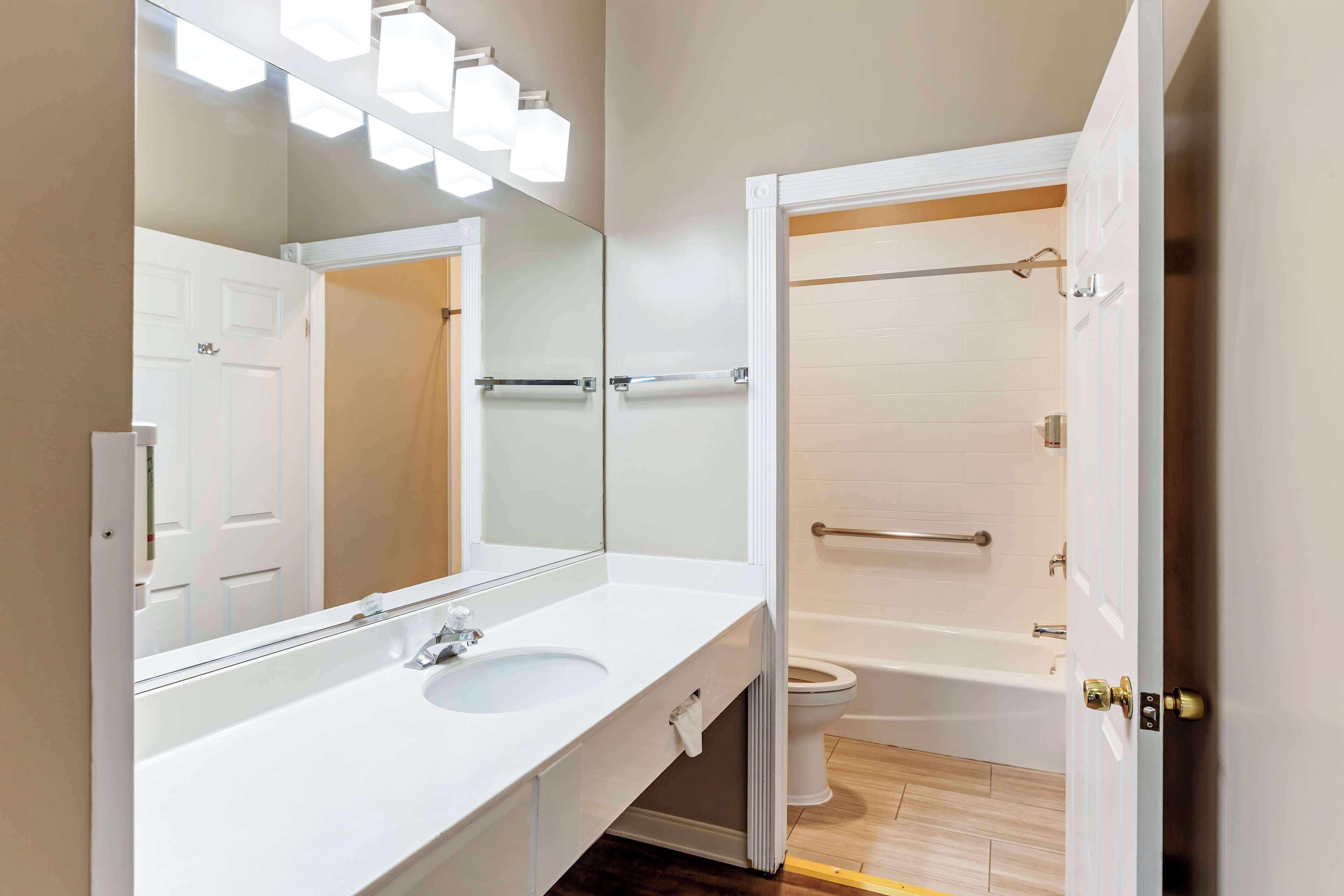 A modern bathroom with a white sink, mirror, and a visible shower area.