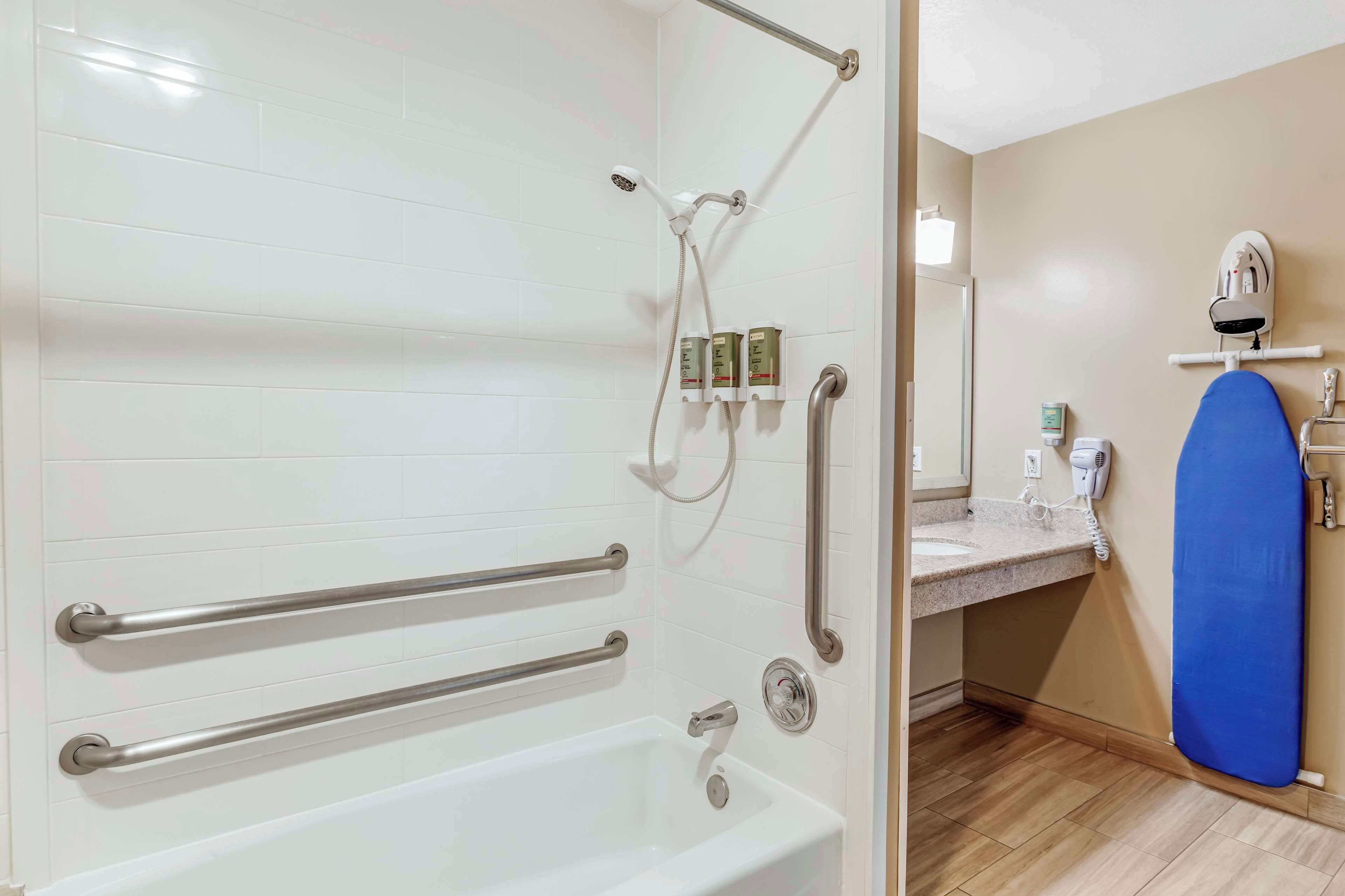 A bathroom with a bathtub, a shower with a handheld showerhead, a towel rack, and a mirror.