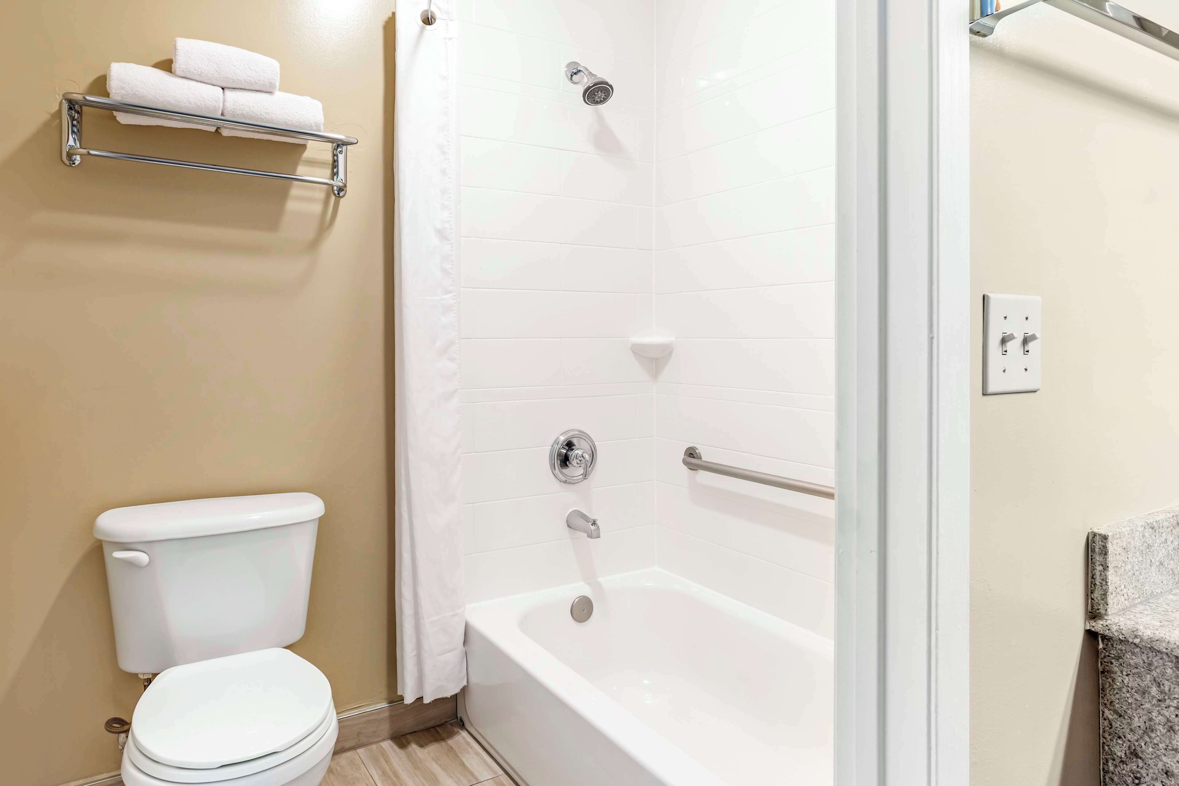 A bathroom with a toilet, a shower with a glass door, and a towel rack with two towels.