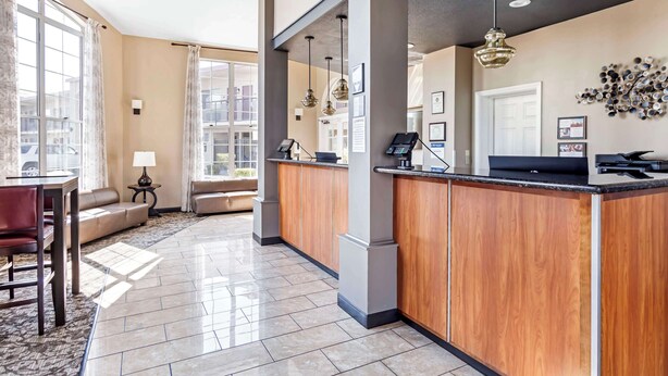 A hotel lobby with a reception desk, a sofa, a dining area, and large windows. - Best Western China Lake Inn (Ridgecrest)