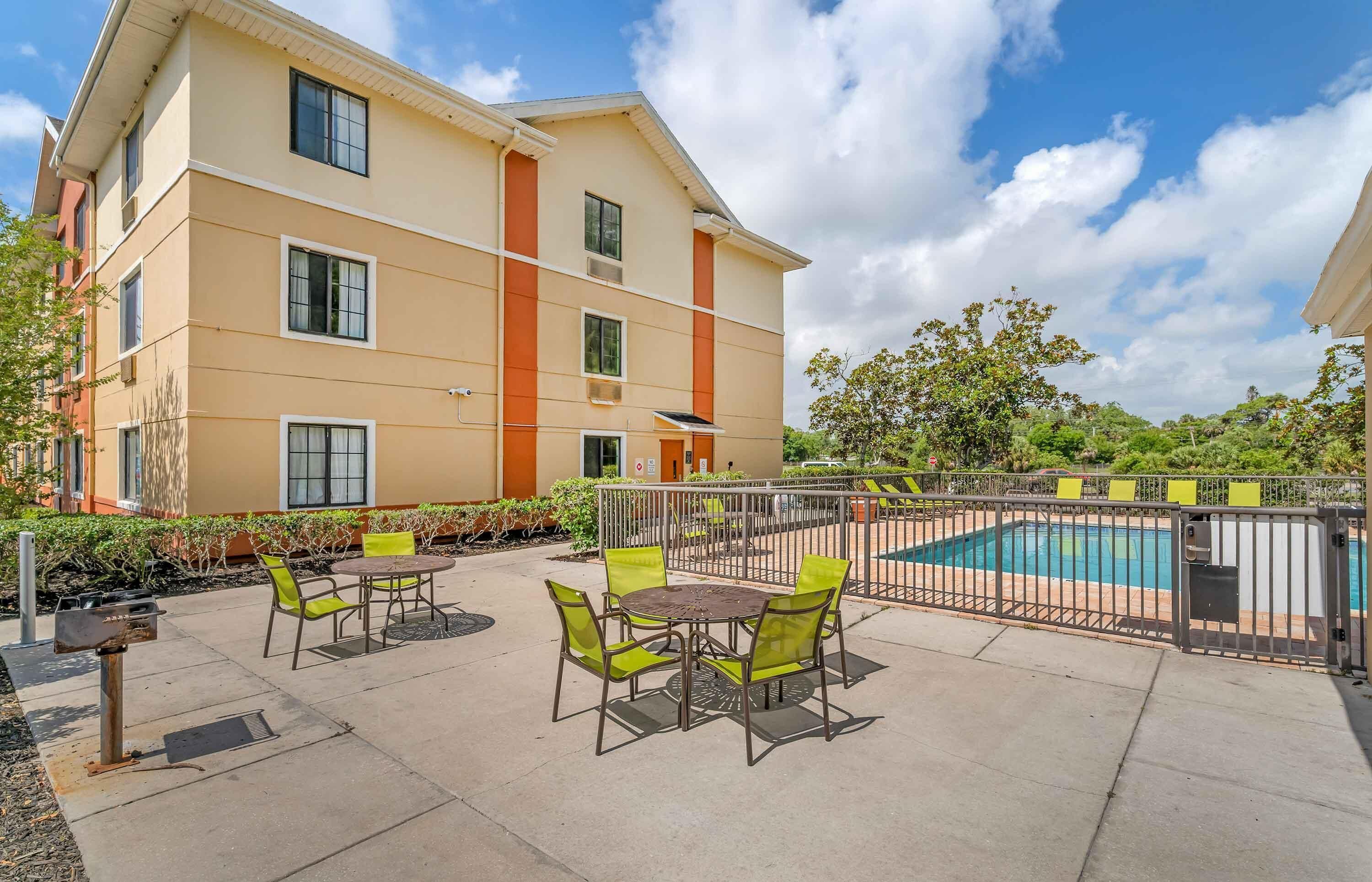 A multi-story hotel with outdoor seating and a swimming pool.