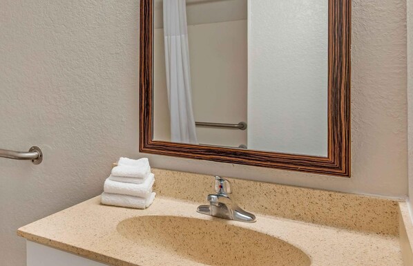 A bathroom with a sink, mirror, and towel rack.