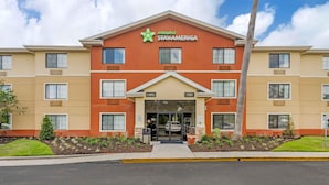Ein mehrstöckiges Hotel mit roter und beiger Fassade, einem Lobbyeingang und einem Schild mit der Aufschrift 'Extended Stay America'.