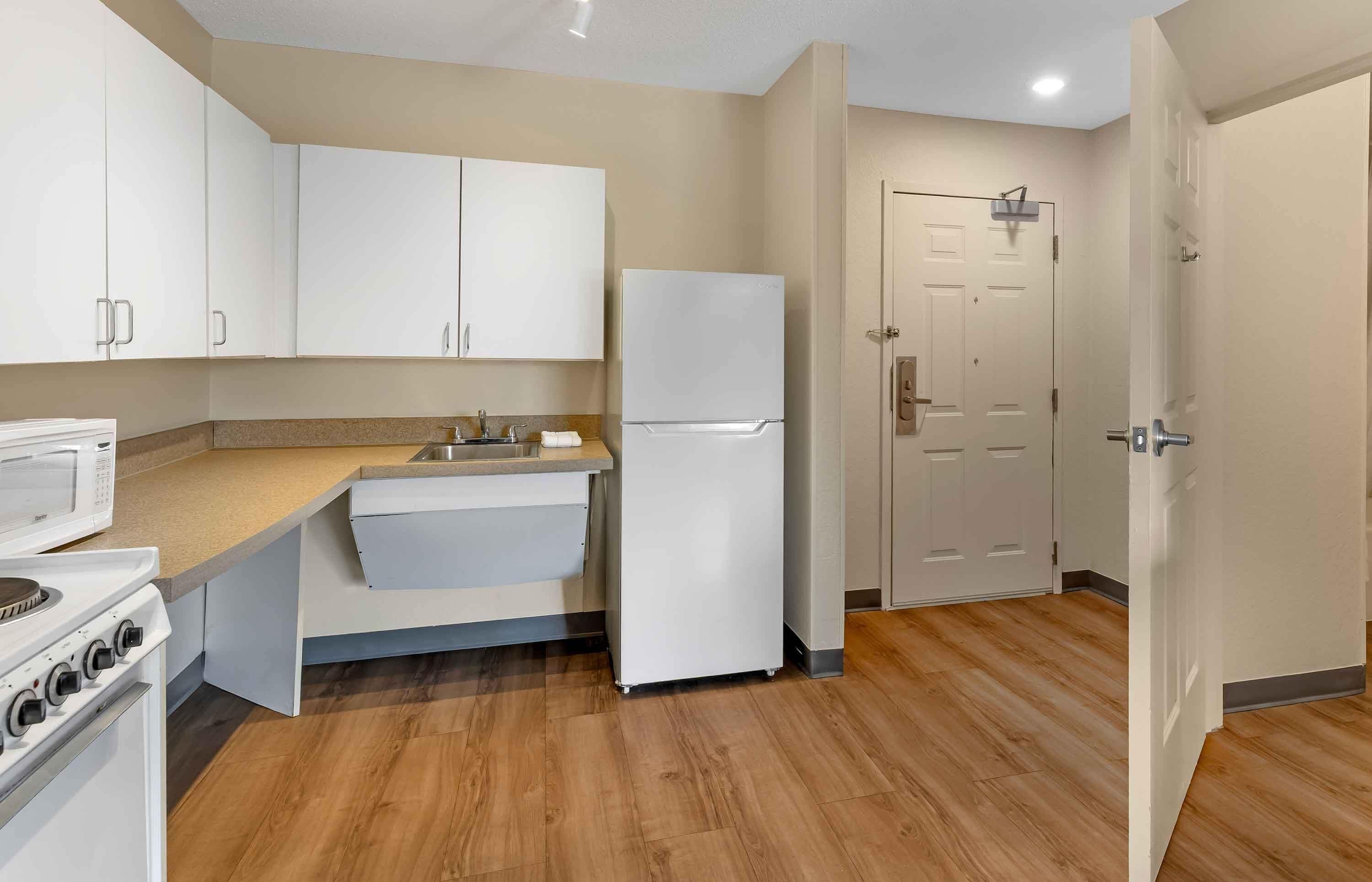 A kitchen with white cabinets, a refrigerator, a stove, and a sink.