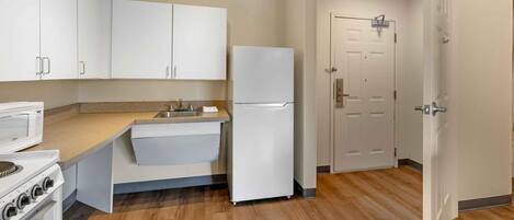 A kitchen with white cabinets, a refrigerator, a stove, and a sink.