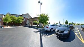 A parking lot with several cars, a building with a brick facade, and a covered walkway. - Country Inn & Suites by Radisson, Benton Harbor-St. Joseph, MI (Benton Harbor)