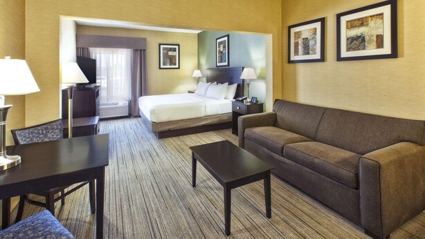 A hotel room with a bed, a sofa, a coffee table, and two lamps. - Country Inn & Suites by Radisson, Benton Harbor-St. Joseph, MI (Benton Harbor)