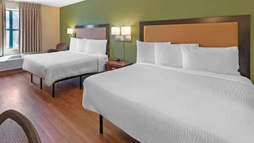 Habitación de hotel con dos camas, una ventana con cortinas, una silla y un calentador instalado en la pared.