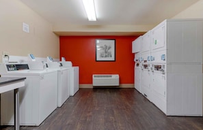 A laundry facility with multiple washing machines and dryers, a control panel, and a framed picture on the wall. - Extended Stay America Suites Los Angeles Torrance Del Amo Ci (Torrance)