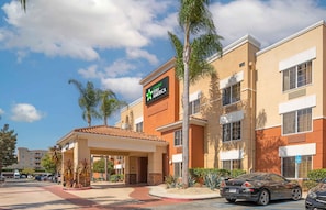A Stay America hotel with a covered entrance, palm trees, and a parking lot.