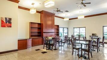 A spacious dining area with multiple tables and chairs, wooden paneling, and ceiling fans.