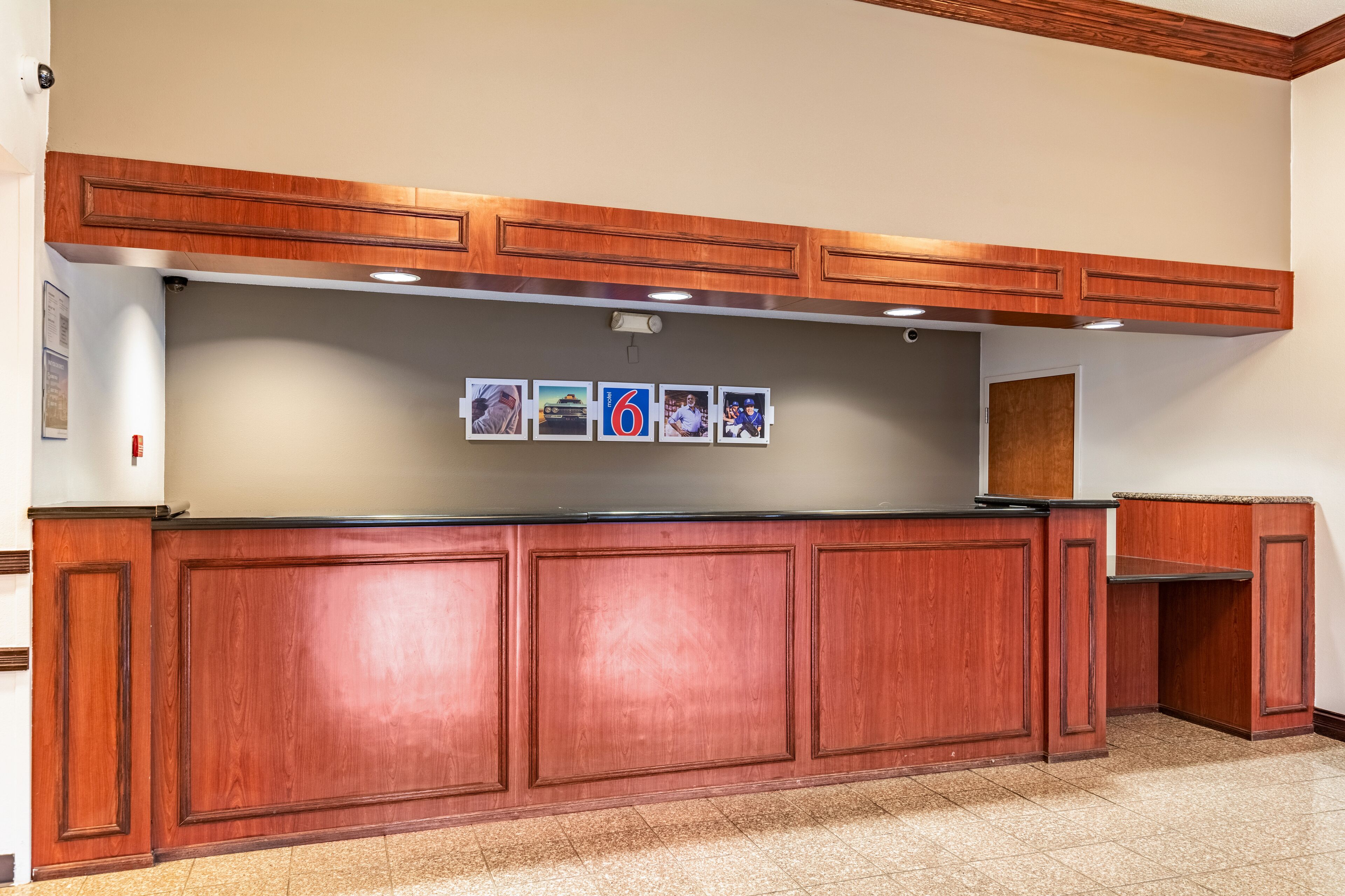 A reception area with a wooden counter, a bulletin board with photos, and a wooden ceiling.